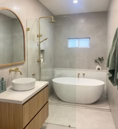 a white bath tub sitting next to a sink in a bathroom under a large mirror