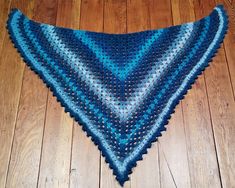 a blue triangle shawl sitting on top of a wooden floor