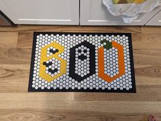 a door mat with the word boo spelled in black and orange letters on top of it