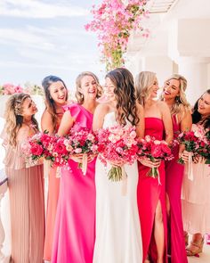 a group of women standing next to each other in dresses and holding bouquets with pink flowers