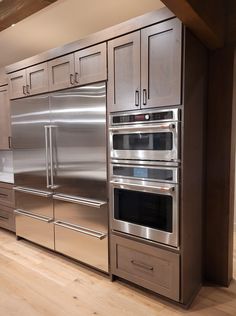 a kitchen with stainless steel appliances and wood flooring, including cabinets in the center