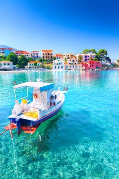 a small boat floating in the clear blue water next to colorful houses and beachfronts