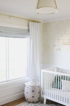 a baby's room with a white crib, blue and white rug and window