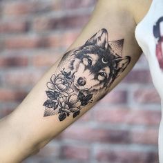 a woman's arm with a wolf and flowers tattoo on the left side of her arm