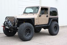 a tan jeep parked in front of a white building