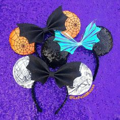 three mickey mouse ears with black and orange bows on purple carpet, one has spider web