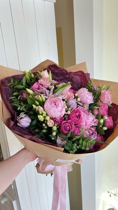 a bouquet of flowers is being held by someone's hand in front of a door