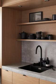 a kitchen with wooden cabinets and black sink faucet in the center, surrounded by shelves filled with pots and pans