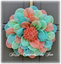 a colorful mesh flower hanging on the side of a door with words happy creations by jan