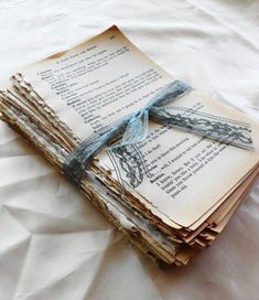 stack of old books tied with blue ribbon on top of white sheeted bedding