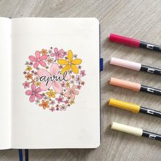 an open notebook with the word april written in it next to some crayons