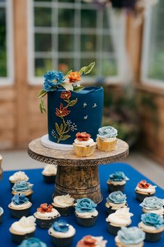 a blue wedding cake and cupcakes on a table