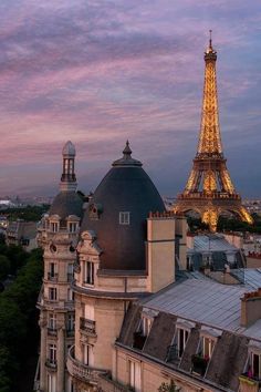 the eiffel tower is lit up at night, with other buildings in the background