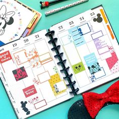 an open planner with mickey mouse stickers on it next to markers and pencils