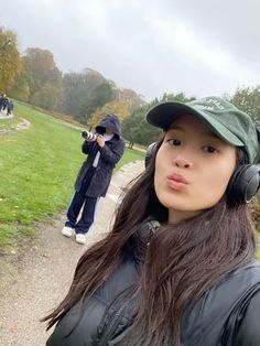 a woman with headphones on taking a selfie in front of a camera man