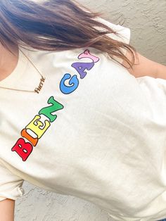 a woman wearing a white shirt with the word happy birthday on it and colorful letters