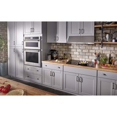 a kitchen with gray cabinets and wooden counter tops