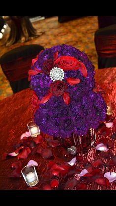 purple and red flowers are arranged in a vase on a table at a wedding reception