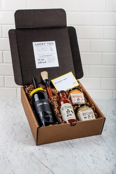 an open box with wine, condiments and sauces in it on a marble countertop