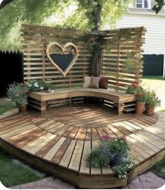 a wooden bench sitting in the middle of a yard next to a tree and potted plants