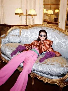 a woman laying on top of a couch in front of a mirror wearing pink pants