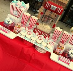 a red table topped with popcorn buckets and cupcakes