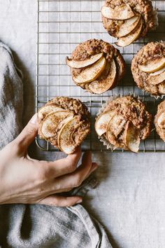 a person is holding some apple pies on a cooling rack