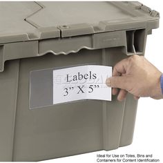 a hand is holding a label on a large plastic container that says labels 3 x5