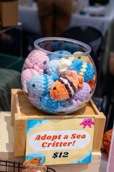 a bowl filled with lots of different colored crochet fish on top of a wooden box