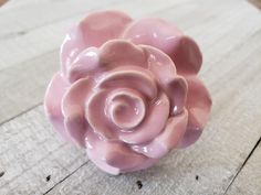 a pink ceramic flower sitting on top of a wooden table