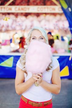 a woman holding a pink lollipop in front of her face