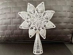 a white crocheted snowflake sitting on top of a couch next to a pillow