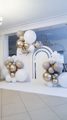 an entrance decorated with white, gold and silver balloons