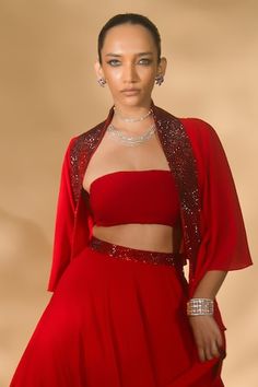 Red lehenga with rhinestone embellished waistband and flared silhouette. Comes with padded blouse and ruffle embellished border cape. - Aza Fashions Red Party Wear Sets For Evening, Embellished Red Sets For Party, Fitted Red Sharara For Evening, Red Evening Choli, Embellished Red Party Sets, Diwali Embellished Lehenga With Cape Sleeves, Diwali Lehenga With Cape Sleeves And Cutdana, Embellished Lehenga With Cape Sleeves For Festivals, Festive Lehenga With Cape