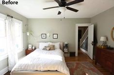 a bed sitting in a bedroom next to a window with a fan on top of it