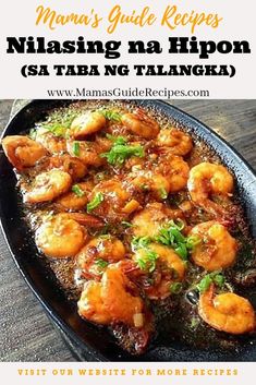 a pan filled with shrimp and sauce on top of a wooden table in front of a white