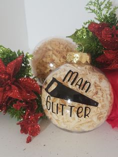 a glass ornament with the words man glitterer on it next to christmas decorations