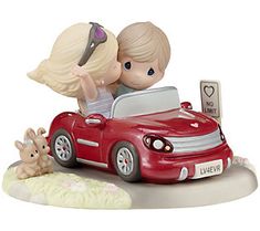 a figurine of two children riding in a red car