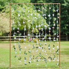 a metal frame with flowers and leaves hanging from it's sides in the grass