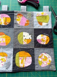 the scissors are laying on the cutting board next to the patchwork piece that has been sewn