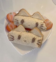 two slices of bread with cat faces on them and strawberries in the shape of hearts