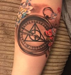 a woman with a tattoo on her arm has a compass and flowers around the wrist