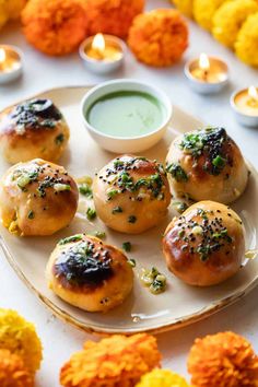 several small rolls on a plate with dipping sauce in the middle and flowers around them