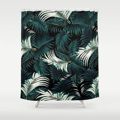 a shower curtain with green and white tropical leaves on it, against a black background