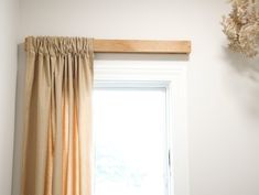 an open window with curtains hanging on the side and a vase in front of it