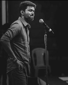 a black and white photo of a man standing in front of a microphone with his hands on his hips