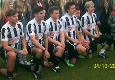 a group of young men sitting next to each other on top of a soccer field