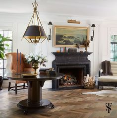 a living room filled with furniture and a chandelier hanging from the ceiling next to a fire place