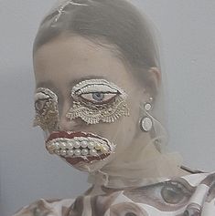 a woman with her face painted in gold and silver, is wearing an elaborate mask