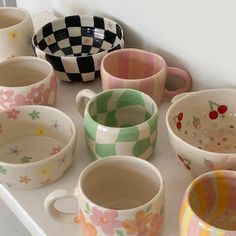 many different colored cups and bowls on a table